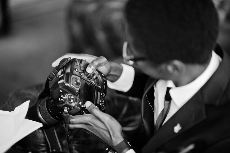 african-american-photographer-paparazzi-man-wear-black-suit-glasses-sitting-office-with-camera-working-laptop_627829-12723